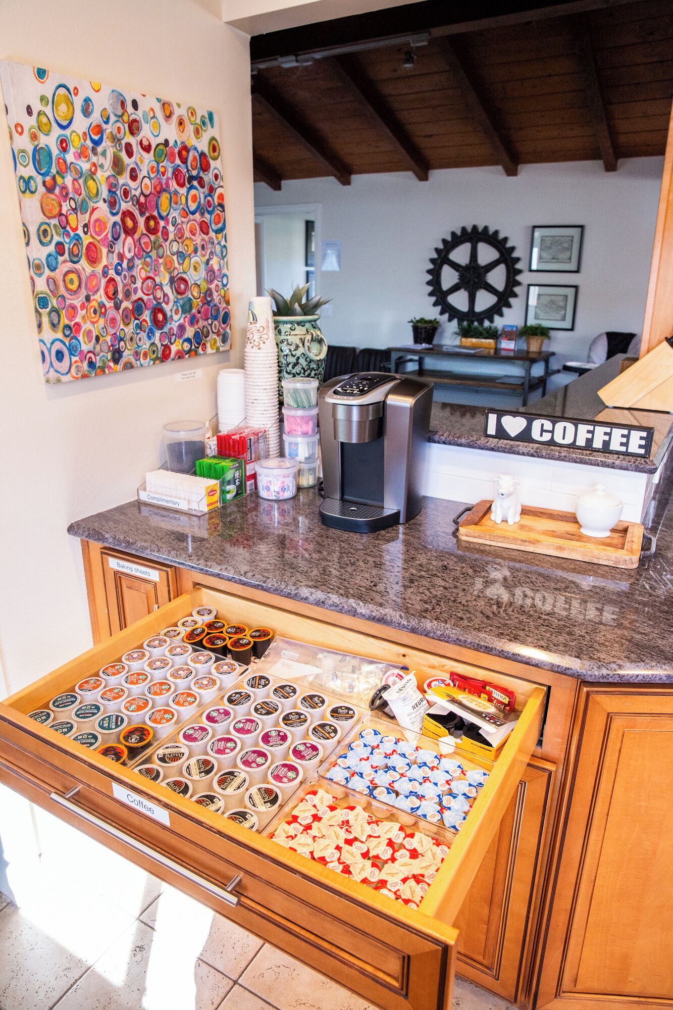A kitchen with a coffee station, a coffee machine, and a variety of coffee pods.
