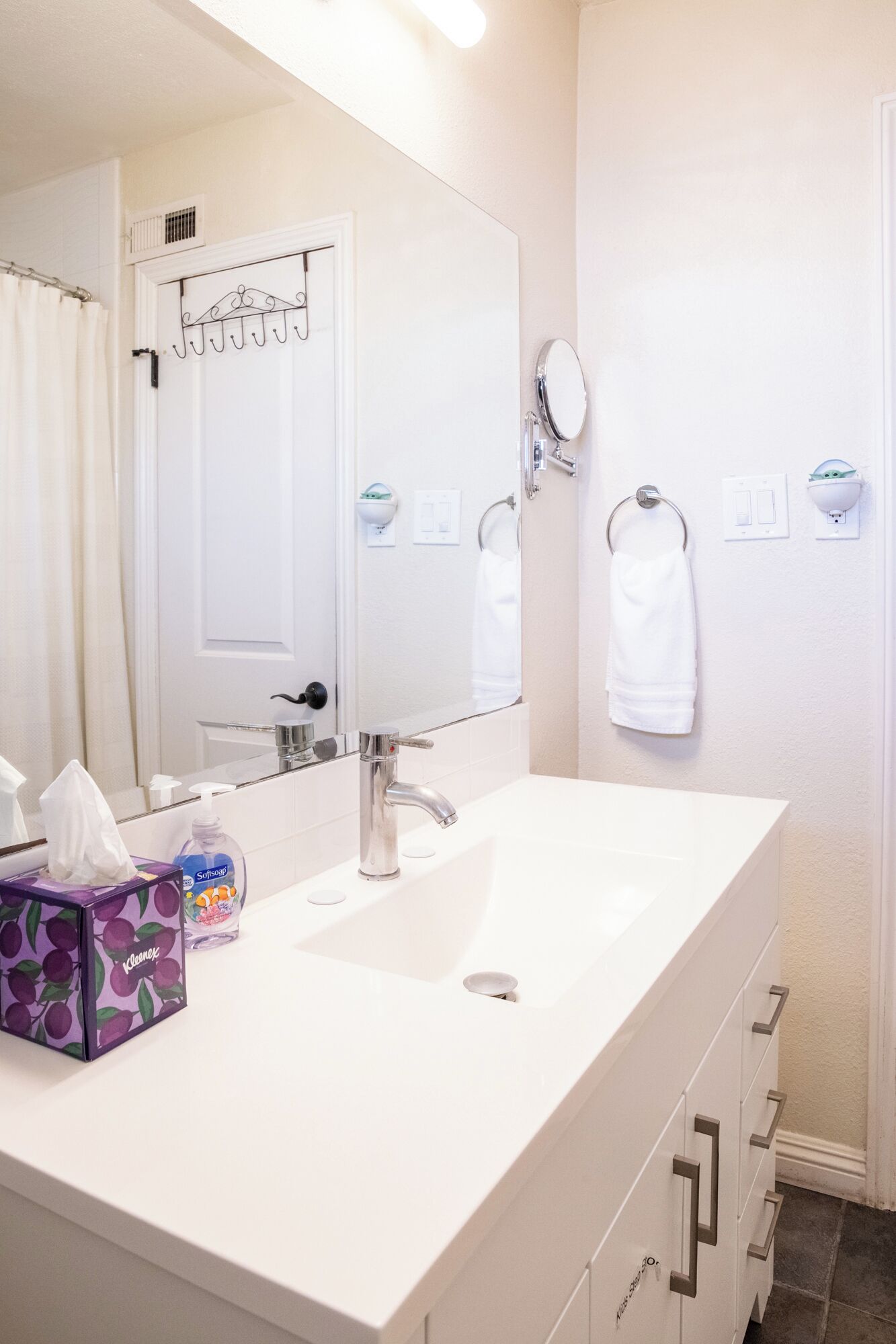A bathroom with a white sink, a mirror, a towel rack, and a toilet paper holder.