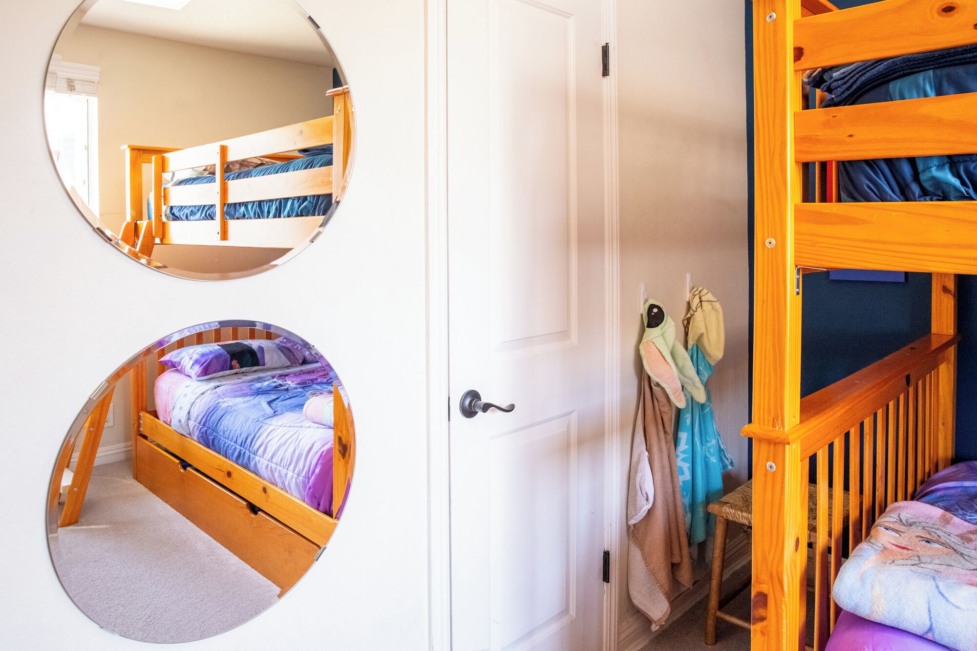 A room with a bunk bed, a door, and a mirror.