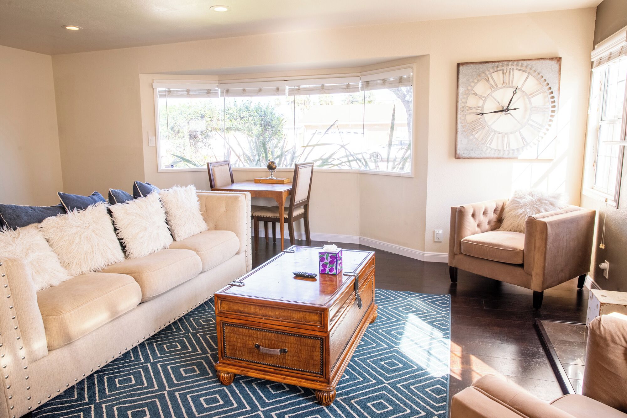A living room with a beige sofa, a wooden coffee table, and a patterned rug.