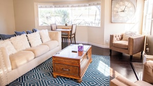Un salon avec un canapé beige, une table basse en bois et un tapis à motifs.