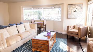 A living room with a beige sofa, a wooden coffee table, and a patterned rug.