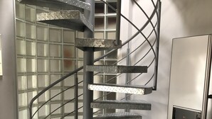 A spiral staircase with metal railings and a water dispenser on the right. - Penthouse 1872 (Bayreuth)