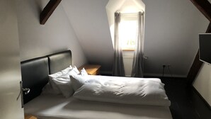 A bedroom with a bed, a nightstand, a window with curtains, and a pendant light. - Penthouse 1872 (Bayreuth)