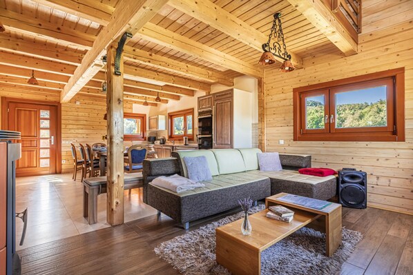 Interior d'una cabana de fusta amb zona de menjador, sofà i cuina.