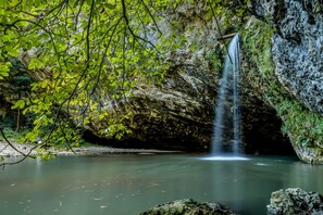 A waterfall in a cave with a pool below. - House Of Nature With Sauna And Tents (Sentjur)