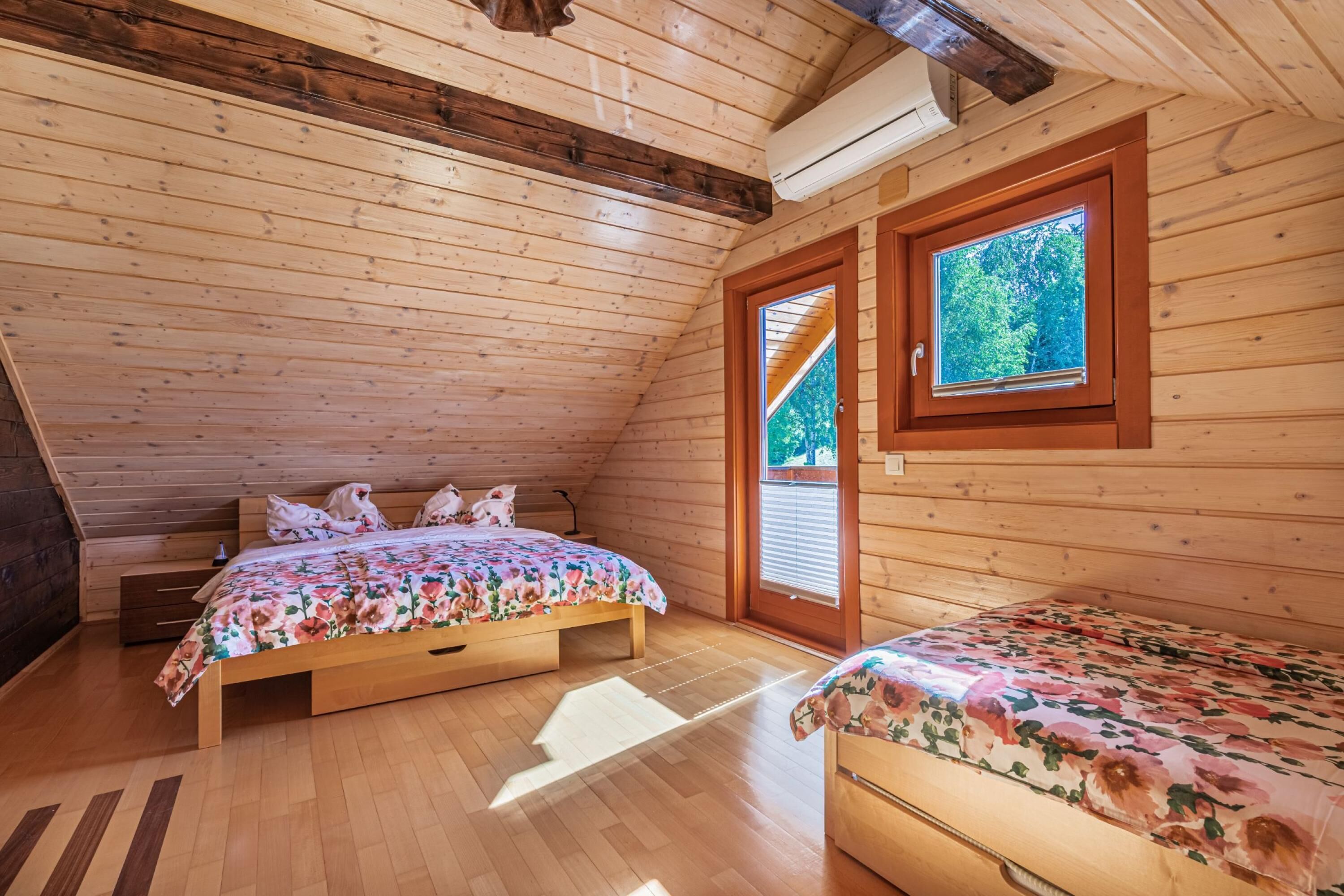 Een houten slaapkamer met een bed, een kinderbed en een raam.