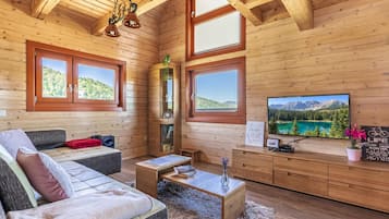 A cozy cabin interior with a sofa, a coffee table, and a TV on a wooden wall.