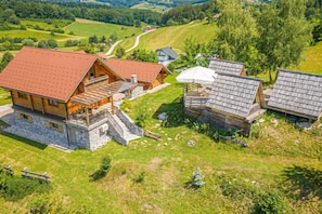 A wooden cabin with a red roof, a stone foundation, and a balcony.
