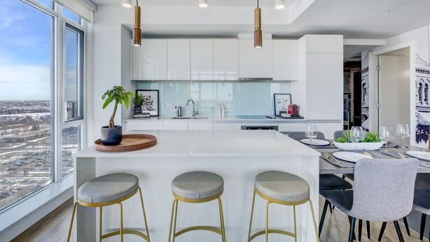 A modern kitchen with a large island, bar stools, and a dining area with a view.