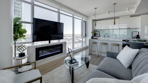 A modern living room with a large TV, fireplace, and city view.