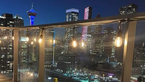 A rooftop terrace with a city view, a table with wine glasses, and a bottle of wine.
