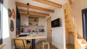 A compact kitchen with wooden beams, a dining table, chairs, a TV, and a staircase. - Cosy chalet in the heart of Monnickendam with terrace (Monnickendam)