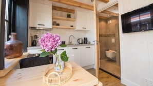 A modern kitchen with white cabinets, wooden beams, and a large TV.