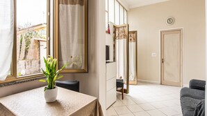 Una habitación con ventana, planta en maceta, mesa, sofá y puerta.