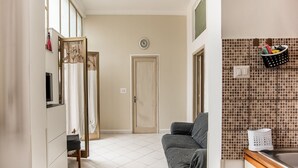 Una sala de estar moderna con un sofá gris, un televisor y un amplio ventanal con cortinas.