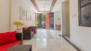 A hallway with a sofa, chairs, a reception desk, and a potted plant. - Sedana Cottage (Pererenan)