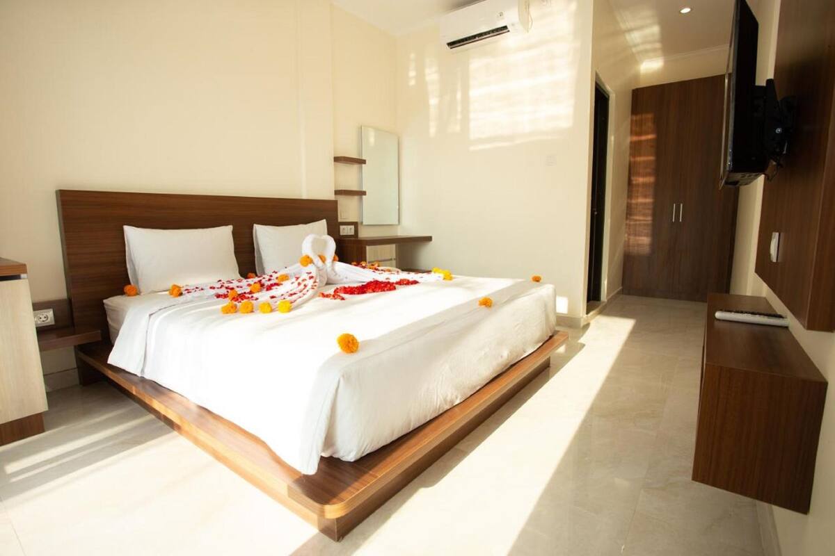 A hotel room with a bed, a TV, and a wooden headboard.