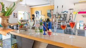 Angolo bar con diversi drink, una bottiglia di Peroni e un vaso con fiori.