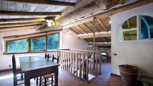 Un interior rústico de madera con una mesa de comedor, una barandilla de madera y un amplio ventanal con vistas a la vegetación.