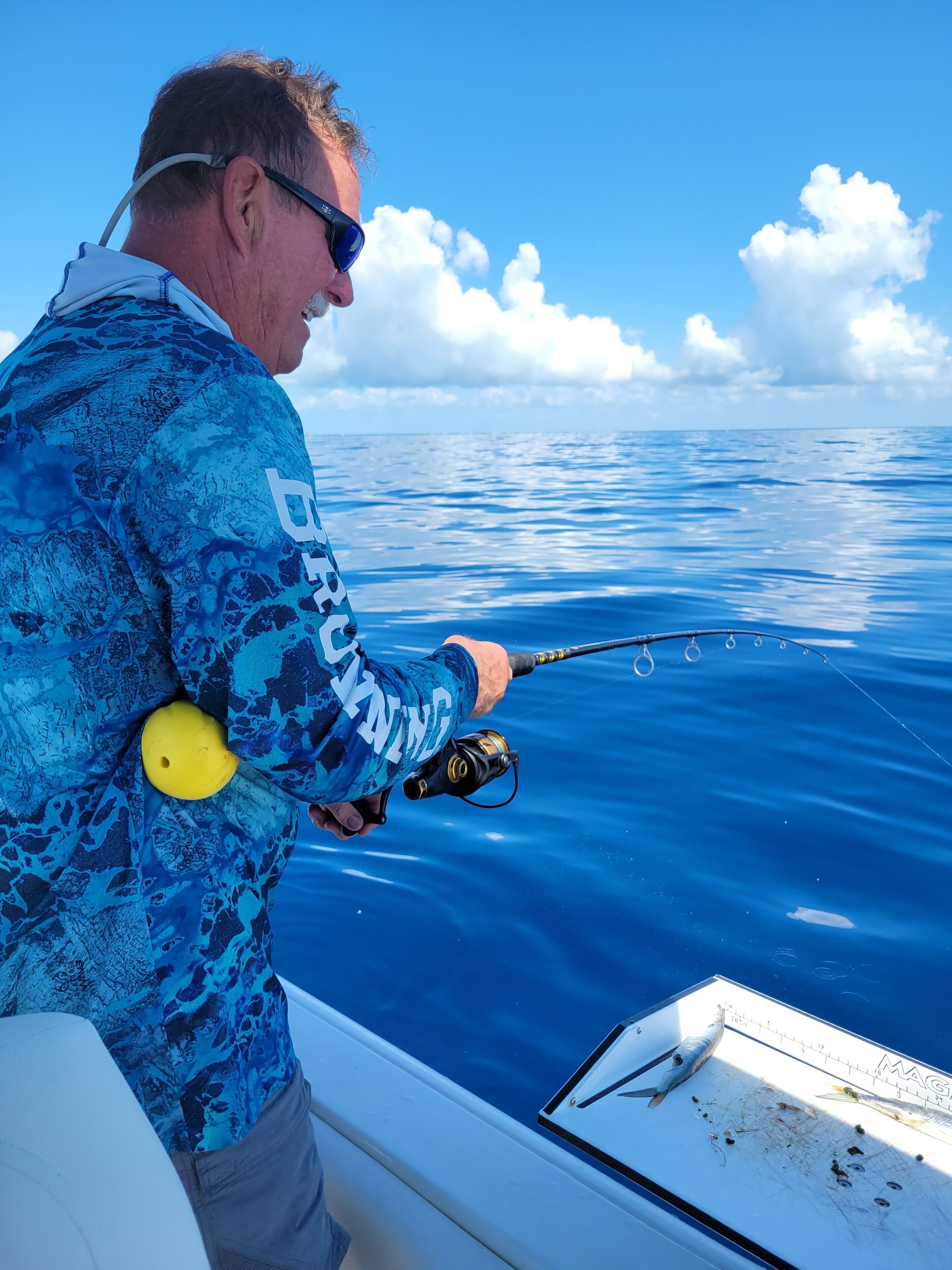 A person fishing on a boat with a clear view of the ocean and sky.