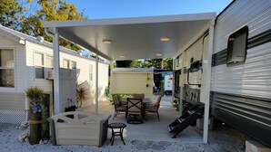 Un'area patio esterna coperta con un tavolo e sedie, circondata da camper.