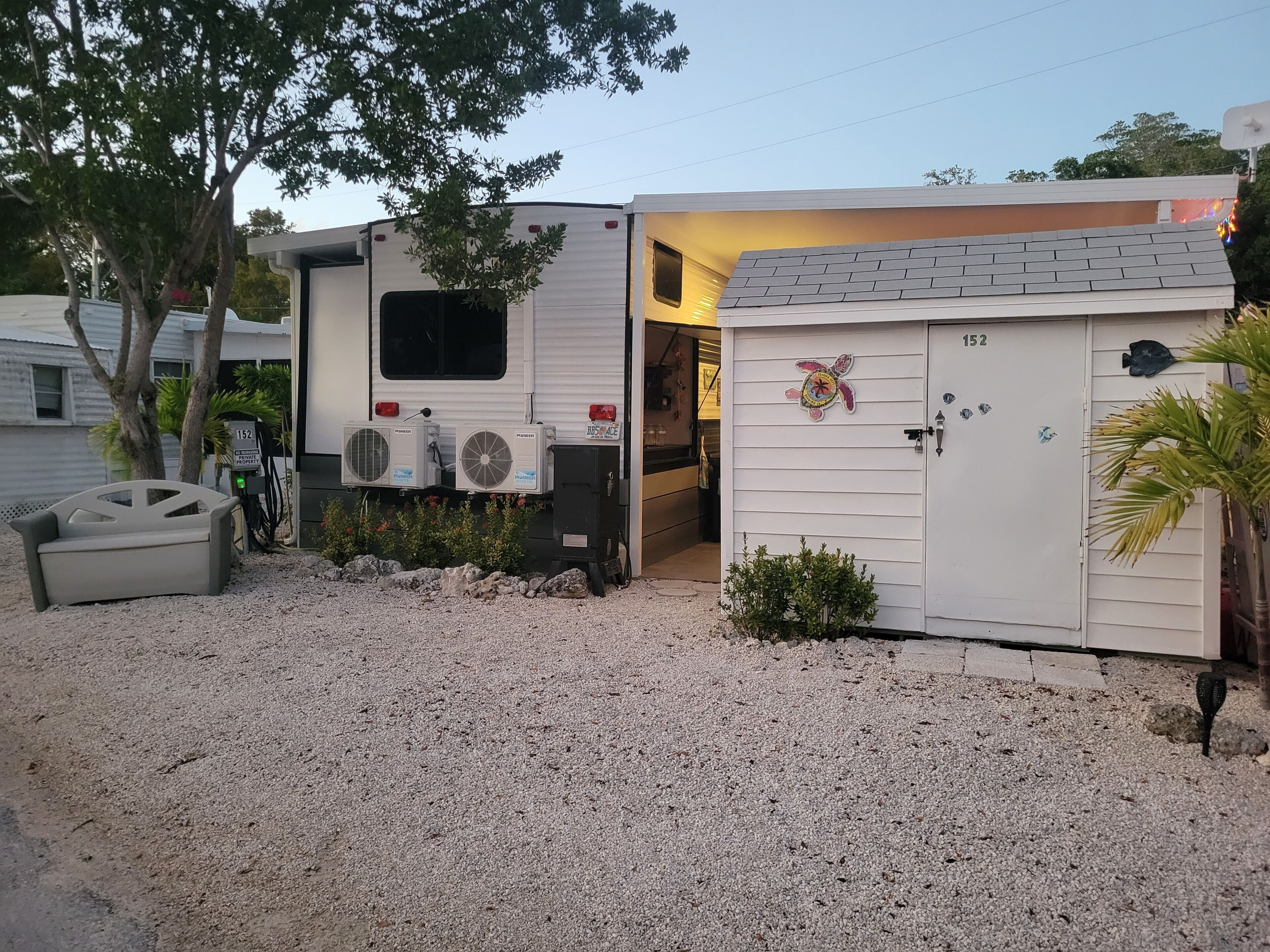 A mobile home with a small attached garage, a gravel driveway, and a mailbox.
