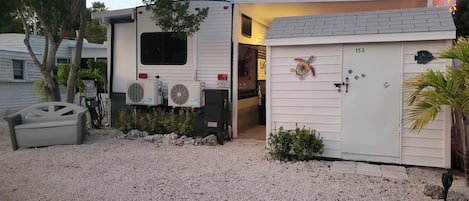 A mobile home with a small attached garage, a gravel driveway, and a mailbox.