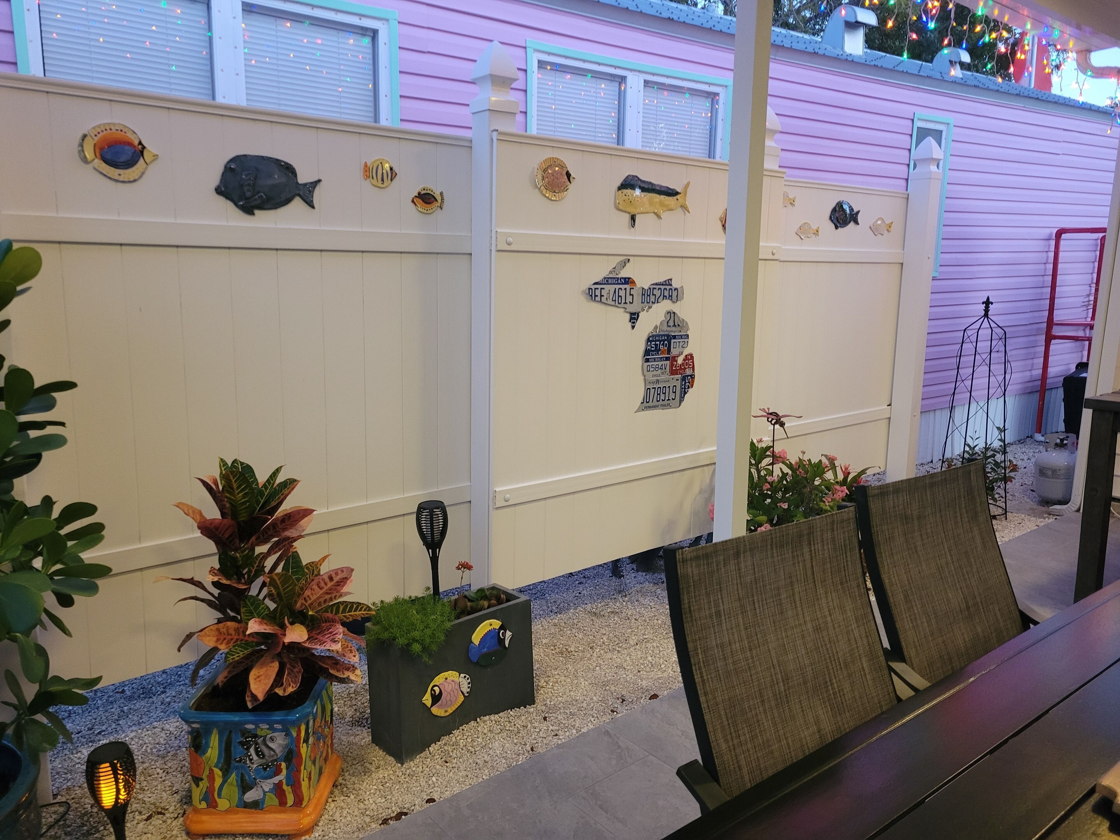 A patio area with a decorative fish wall, potted plants, and outdoor seating.