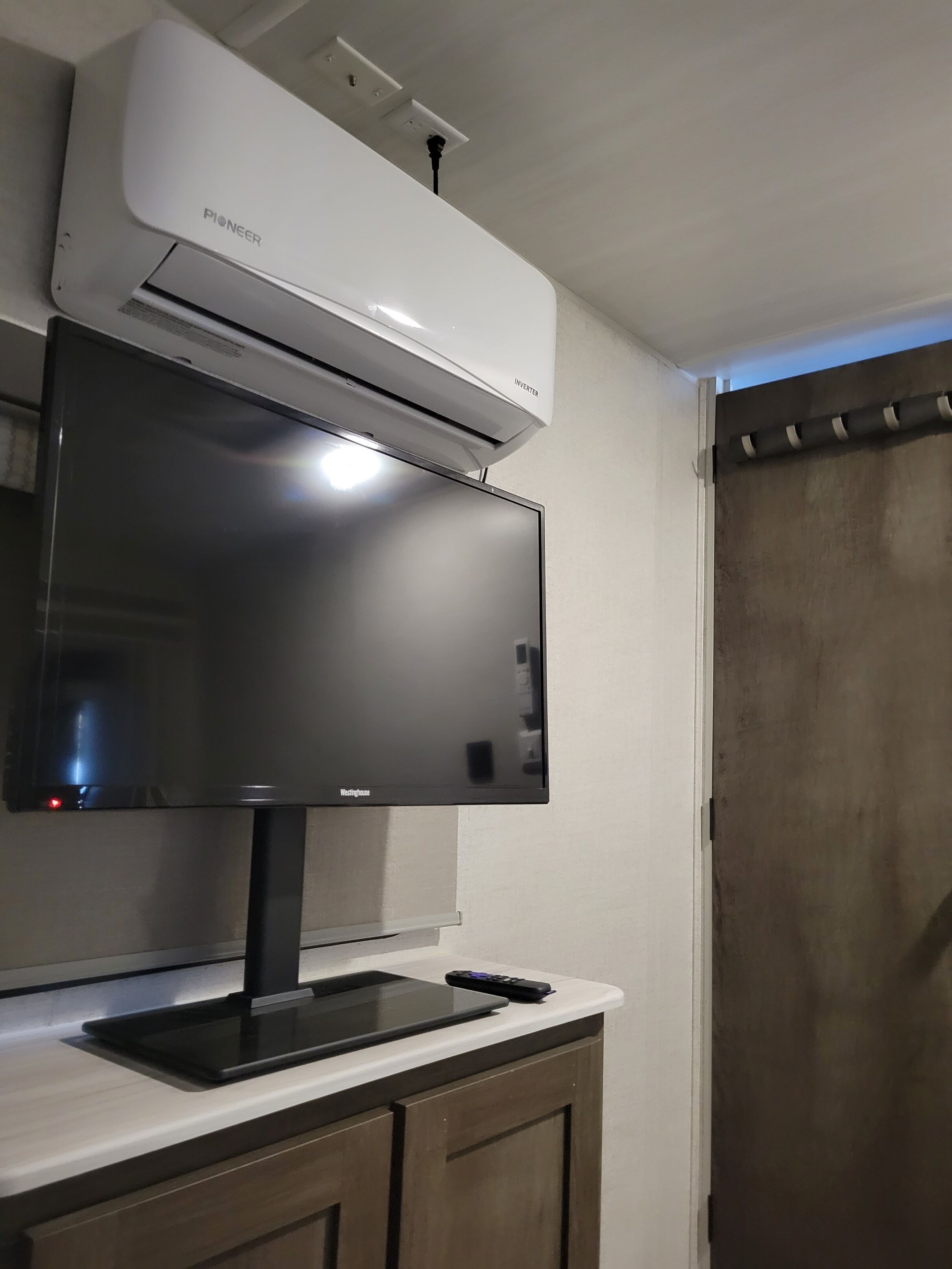 A kitchen with a flat-screen TV, a Pioneer air conditioner, and a Westinghouse microwave.