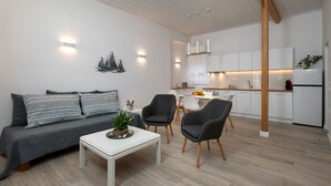 A modern living room with a sofa, chairs, a coffee table, and a kitchen in the background. - Studio with breathtaking views of the sea (Corfu)