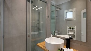 A modern bathroom with a glass shower enclosure, a large white sink, and a wooden vanity. - Studio with breathtaking views of the sea (Corfu)