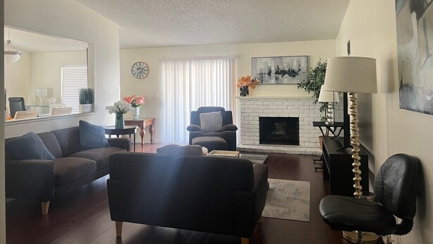 A living room with a fireplace, a sofa, a chair, and a lamp. - One story 3 bedroom home-10 minutes to strip (Las Vegas)