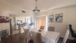 A dining area with a table, chairs, and a kitchen in the background. - One story 3 bedroom home-10 minutes to strip (Las Vegas)