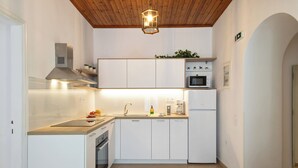 A compact kitchen with white cabinets, a microwave, a stove, and a sink. - Two bedroom apartment with breathtaking views (Corfu)