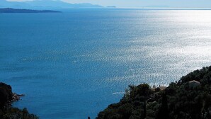 A coastal view with a clear sky, calm sea, and distant mountains. - Two bedroom apartment with breathtaking views (Corfu)