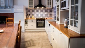 Una cocina con armarios blancos, una campana extractora negra, salpicadero de azulejos y una mesa de comedor de madera.