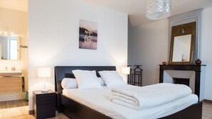 Un dormitorio moderno con una cama grande, mesitas de noche, un espejo y una chimenea.