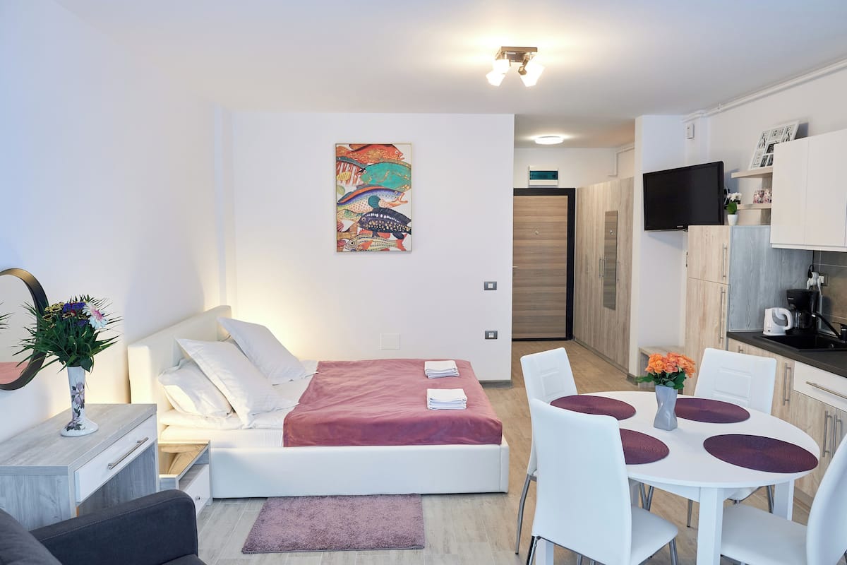 A modern bedroom with a bed, bedside table, and a painting on the wall.