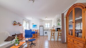 En kompakt opholdsstue med sofa, spiseplads, køkken og et træskab.