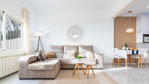 A modern living room with a sectional sofa, a round coffee table, and a dining area with a table and chairs.