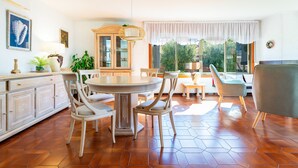 A spacious dining area with a round table, white chairs, and a cabinet with glass doors. - Villa Monbijou with Private Pool & Wi-Fi close to the Beach (Vinarós)
