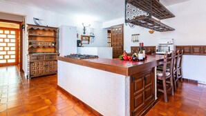 A kitchen with a central island, wooden cabinets, a microwave, and a wine rack. - Villa Monbijou with Private Pool & Wi-Fi close to the Beach (Vinarós)