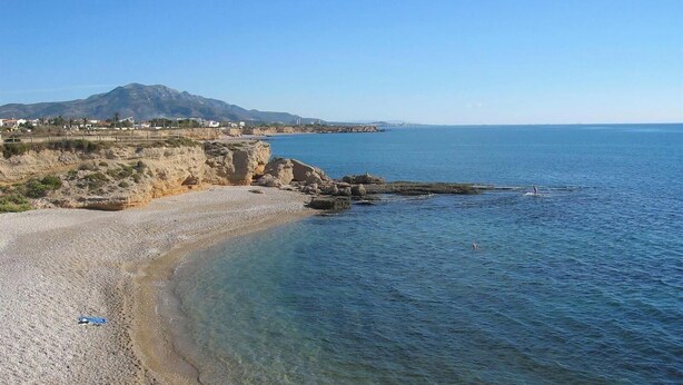 A coastal beach with clear waters, rocky shoreline, and a distant mountain. - Villa Monbijou with Private Pool & Wi-Fi close to the Beach (Vinarós)