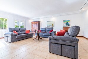 Uma sala de estar com dois sofás cinzas, uma mesa de centro de madeira e um armário.