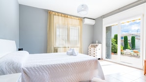 Una camera da letto con un letto, una cassettiera, una finestra con tende e vista all'esterno.