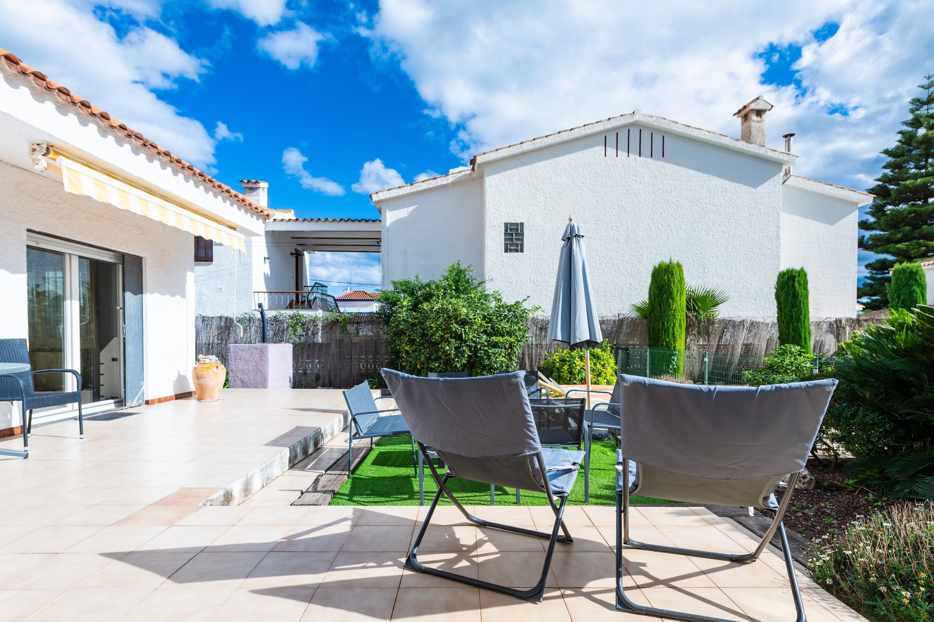 Un patio con dos sillas, una mesa y una sombrilla.