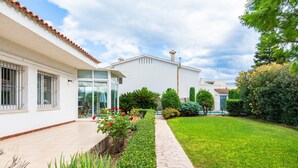 Una casa moderna con tetto in tegole, patio lastricato e giardino curato.