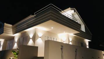 A modern house with a flat roof, large windows, and a balcony.