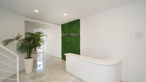 A reception area with a white reception desk, a green wall with the word 'COSTADELLA,' a potted plant, and a marble floor. - Apartment Costa Bella close to the Beach with Shared Pool & Wi-Fi (Altea)
